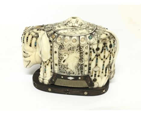 An Early 20th century carved ivory elephant inlaid with mother of pearl and other stones 12x9cm some (stones missing.)