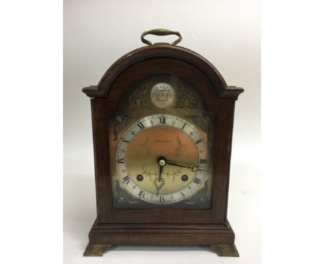 An oak mantle clock by The Alexander Clock Co., the metal dial with gilt mounts