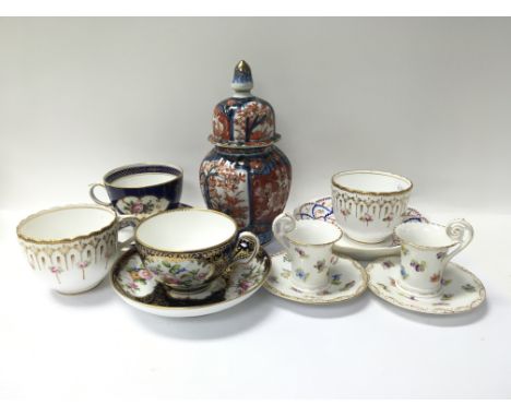 A selection of circa 19th century cups and saucers alongside an Imari jar with cover.
