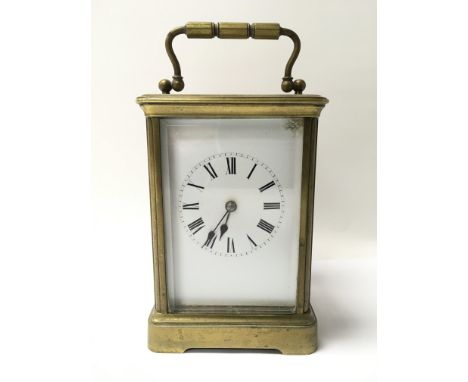 A brass cased carriage clock with white dial presenting black Roman numerals.