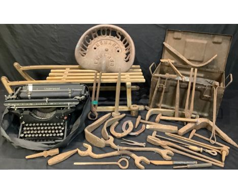 A cast iron tractor seat, Nicholsons, Newark; an Underwood typewriter; a vintage wooden sledge; a metal ammunition box contai