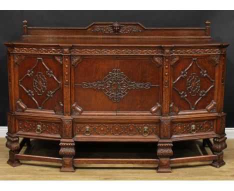 A Jacobean Revival oak sideboard or serving cabinet, shaped half gallery centred by a Green Man mask above a pair of central 