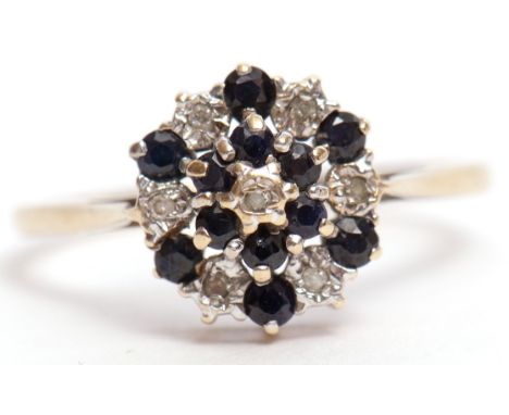 9ct gold sapphire and diamond cluster ring, the flowerhead featuring 12 small circular cut sapphires and 7 small single cut d