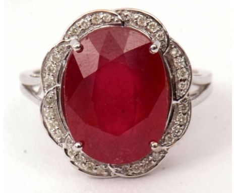 Modern ruby and diamond cluster ring, the oval faceted ruby 12 x 10mm, within a surround of small single cut diamonds, basket