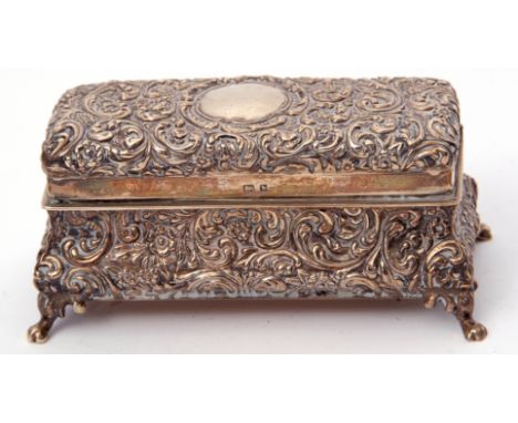 Edwardian silver dressing table ring box of casket form, the bombe shaped base supported on four claw feet, the hinged lid op