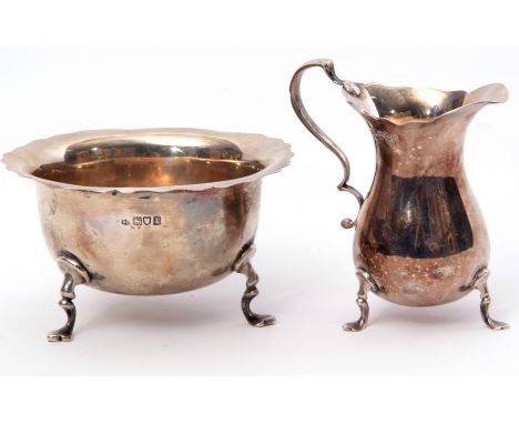 Edward VII cream jug of pear shape with card cut rim and double C scroll handle on three curved feet, together with a matchin