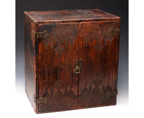 AN ARTS AND CRAFTS TOOLED LEATHER TABLE CABINET with decorative pierced metalwork and panel doors, 43cm wide x 28cm deep