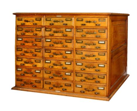 A LIGHT OAK CARD INDEX CABINET fitted 21 drawers with brass handles and label plates, with moulded panel sides on plinth base