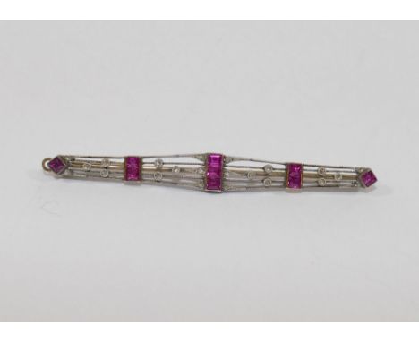 An Art Deco bi-colour ruby and diamond set bar brooch, unmarked, 6.8cm long, 5.4g gross CONDITION REPORTS & PAYMENT DETAILS I