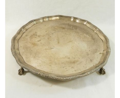 A circular silver tray, Sheffield 1956, by Thomas Bradbury and Son, with wavy gadrooned rim, raised on three claw and ball fe