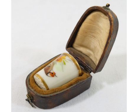 An early 20th century Royal Worcester porcelain thimble, with puce factory mark, hand-painted with a goldfinch on a flowering