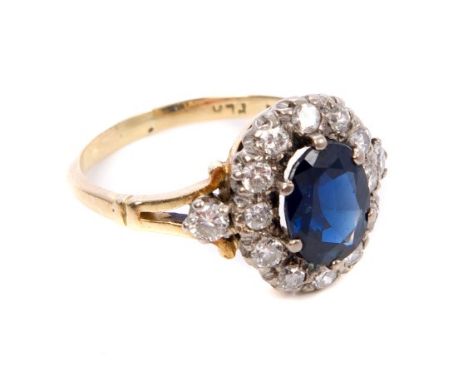 Victorian-style sapphire and diamond cluster ring with an oval mixed cut blue sapphire surrounded by a border of brilliant cu