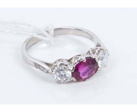 Ruby and diamond three stone ring with central oval mixed cut ruby weighing approximately 1.15 carats, flanked by two brillia