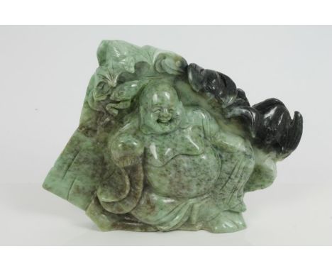 Large jade or green hardstone relief carving depicting a laughing Buddha, seated holding a peach, surrounded by bats, 27cm wi