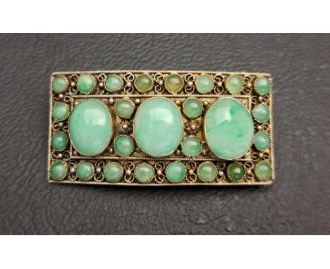 CHINESE JADE SET SILVER BROOCHthe curved rectangular brooch set with three larger oval jade cabochons, surrounded by smaller 