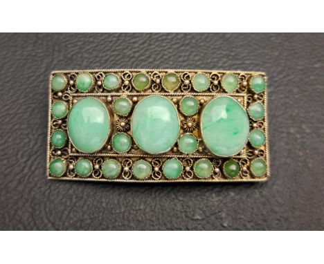 CHINESE JADE SET SILVER BROOCHthe curved rectangular brooch set with three larger oval jade cabochons, surrounded by smaller 