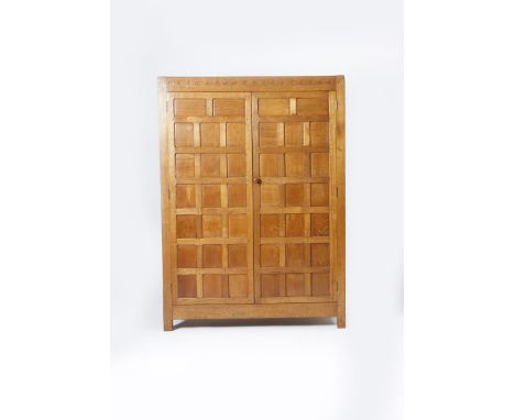 A Robert Mouseman Thompson oak wardrobe,  rectangular with hinged panel doors and carved arch mantel, panelled side, with car