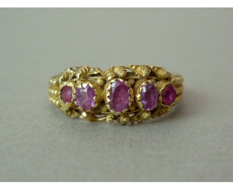 A Victorian ruby dress ring, with five graded stones rub-set to the cannetille decorated and spirally pelleted face, on a con