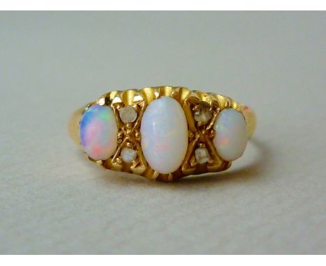 A late Victorian opal and diamond dress ring, the face set with three oval cabochon stones, the largest approximately .28ct, 