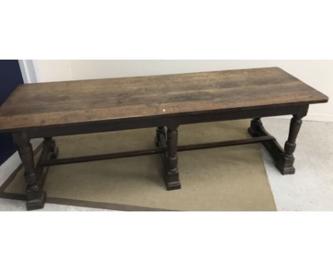 An 18th Century and later oak refectory style dining table, the plank top above a plain frieze on six turned and ringed suppo