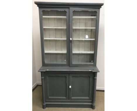 A modern painted pine dresser with canted cornice over two glazed doors enclosing a painted interior with four shelves on a b