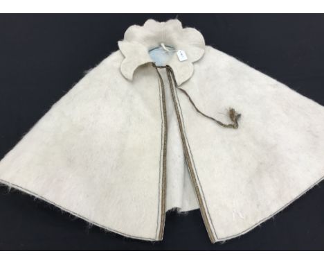 A cream felted wool cape with applied braid and piping decoration with a wired stand up petal collar and pale blue moire taff