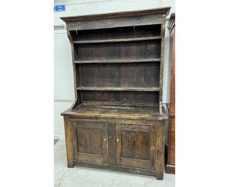 An oak dresser in the 18th Century manner, the three tier boarded plate rack with cup hooks over two panelled doors on stile 