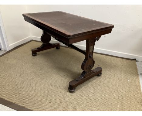 A Victorian rosewood library table, the rectangular top with insert writing surface on rectangular end pillar supports, unite