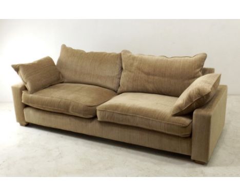 A modern four seater sofa with loose cushions to back and sides, upholstered in beige velour fabric, 245 by 100 by 90cm high.