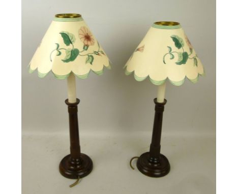 A pair of modern wooden bedside lamps, the candlestick bases with brass fittings and printed paper scalloped shades, 53cm hig