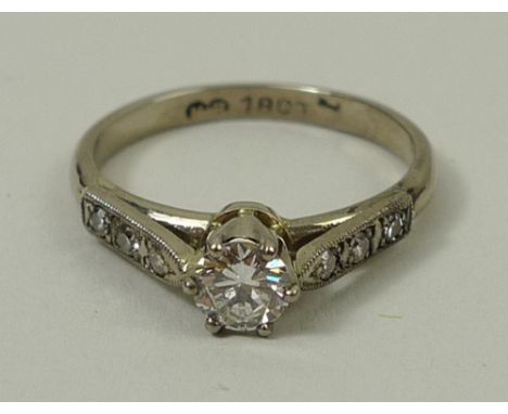 An 18ct gold and diamond solitaire ring, the central diamond, approximately 0.5ct, flanked by three diamonds to each shoulder