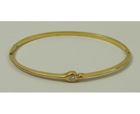 An 18ct gold and solitaire diamond set bangle, approximately 1/8ct, 8.0g.