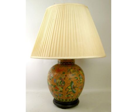 A 20th century Chinese ceramic table lamp of ovoid form, the rose orange ground decorated with flowers and butterflies, and a