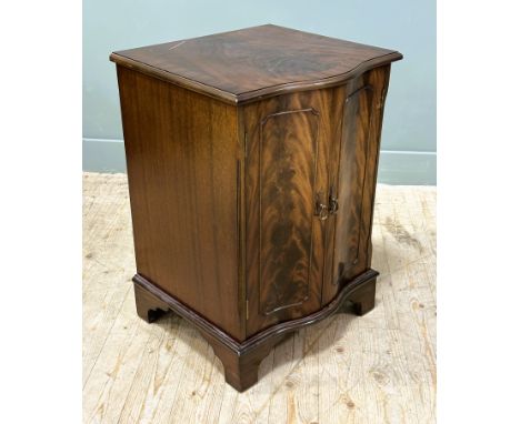 A modern mahogany serpentine front drinks cabinet, with hinged top and double doors, raised on bracket feet: h.x 74cm l.x 52c