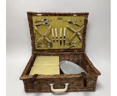 A Brexton wicker picnic basket containing a part travel dinner service of four knives, four spoons, four forks, three bowls, 