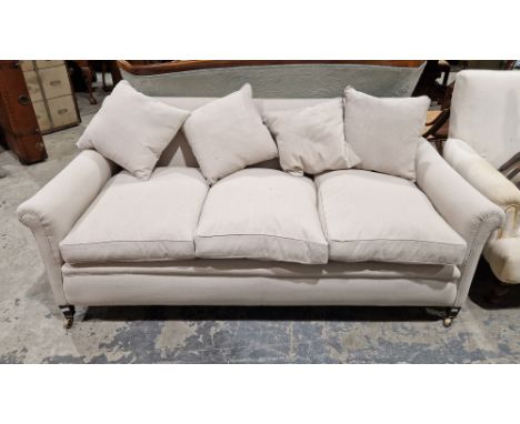 A contemporary grey upholstered three-seater sofa with four additional cushions, raised on metal castors, measuring approx 75