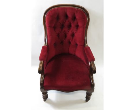 A Victorian button back armchair on turned legs