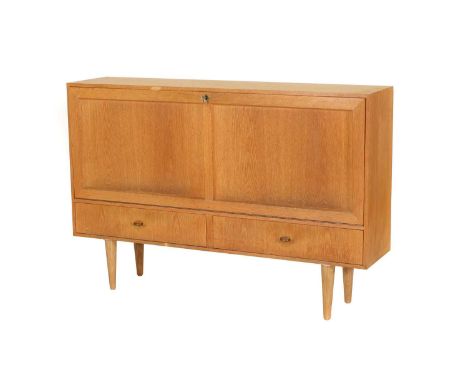 A Danish oak cabinet,1960s, with a fall front enclosing two divisions, each with a single shelf, over two drawers, raised on 