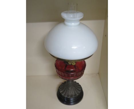 A late 19th century oil lamp - cranberry bowl above a moulded stem on a marble base - good funnel and shade - in good conditi