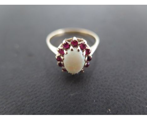 A 9ct yellow gold opal and garnet dress ring, the large oval opal surrounded by twelve small garnets, size R,approx 2.2 grams