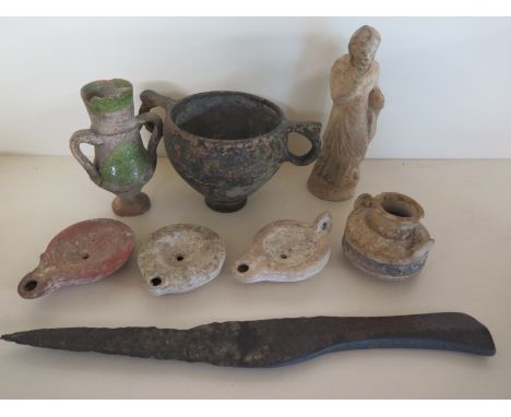 A selection of antiquities including Roman oil lamps, twin handled cup, an early dagger and a clay figure
