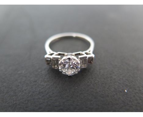 A platinum and diamond ring with a central diamond, flanked either side by two baguette cut diamonds - ring size L - approxim