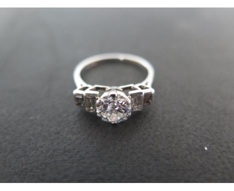 A platinum and diamond ring with a central diamond, flanked either side by two baguette cut diamonds - ring size L - approxim