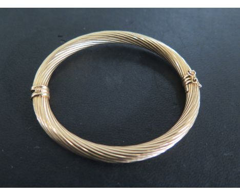 A 9ct yellow gold bangle with sprung hinge - 7.5 x 6.5cm - approximately 8 grams - in good condition