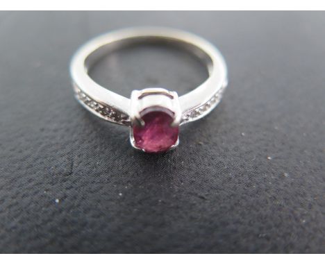 A 9ct white gold and ruby ring - the ruby flanked by small diamond chips - ring size N - surface scratches and usage wear - a