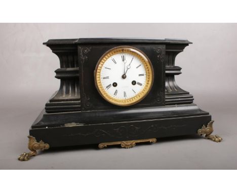 A large black slate mantle clock. Comprising of a white enamel dial with roman numerals and marked R Heslop. Decorated with t