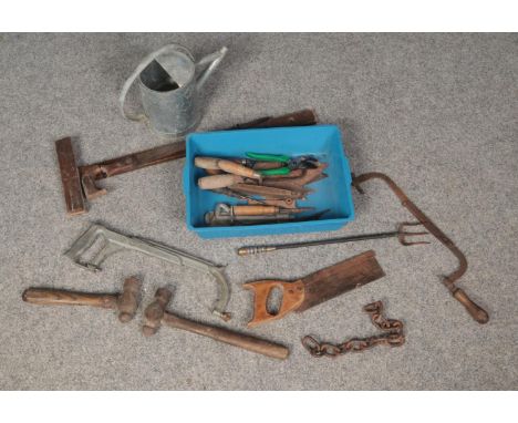 A box of tools. Including hammers, saws, water can, etc.  