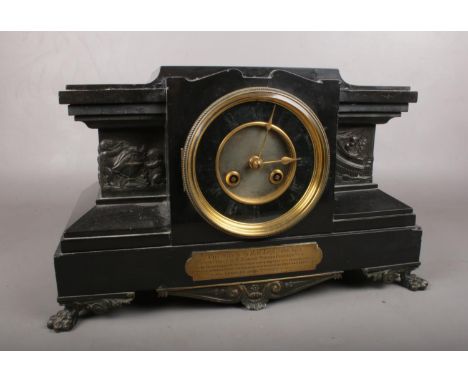 A large black Slate mantle clock. Comprising of a black and gilt dial, Lion feet and a brass presentation plaque inscribed wi