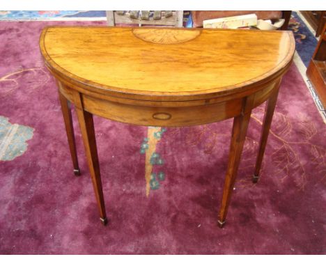 A George III mahogany demi lune fold over card table, with double swing action, the top crossbanded, ebony strung and inlaid 