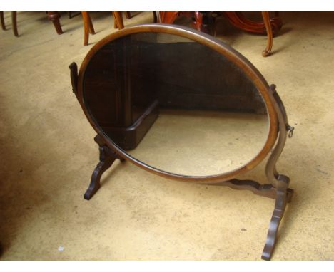 A Georgian style mahogany large oval skeleton swing toilet mirror, on scroll supports.